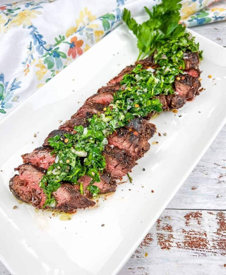 Sliced Grilled Hanger Steak with Chimichurri on a white plate.