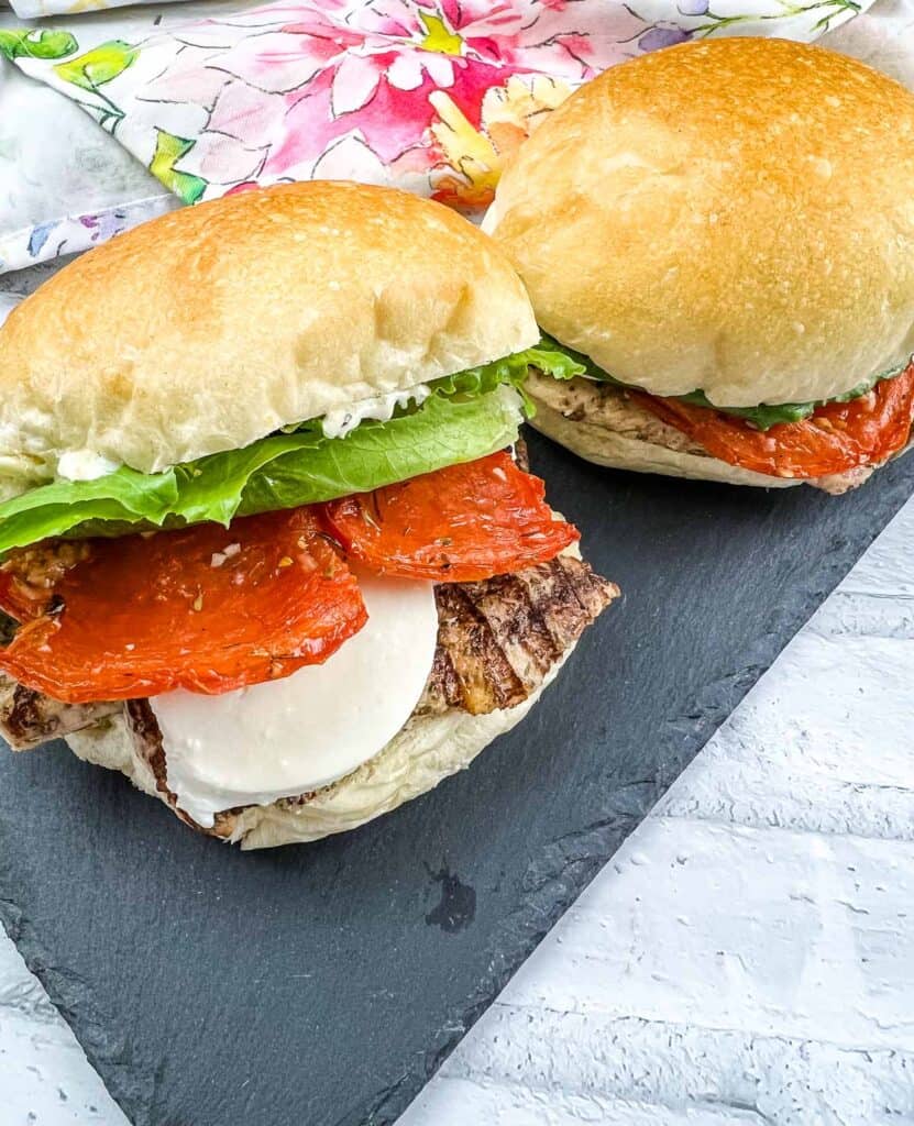 Grilled Chicken Caprese Sandwiches on a black plate.