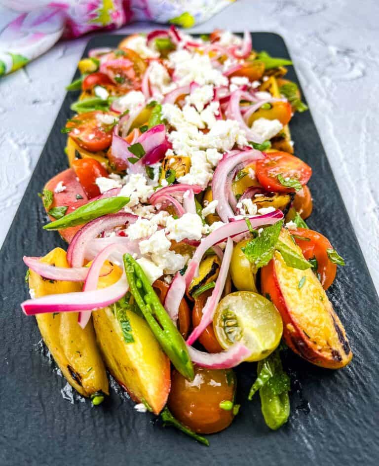 Grilled Peach Salad with Tomatoes on a black platter.