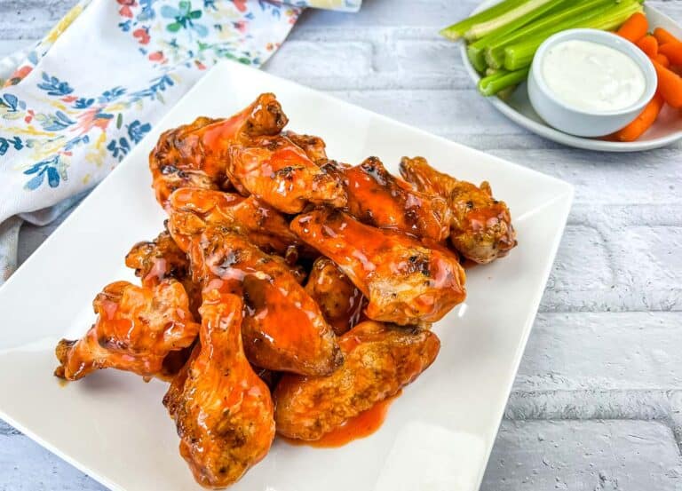 Grilled Wings with Buffalo Sauce served in a white plate with sauce in the background