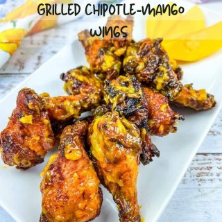 Grilled chicken wings and mango on the side on a white plate.