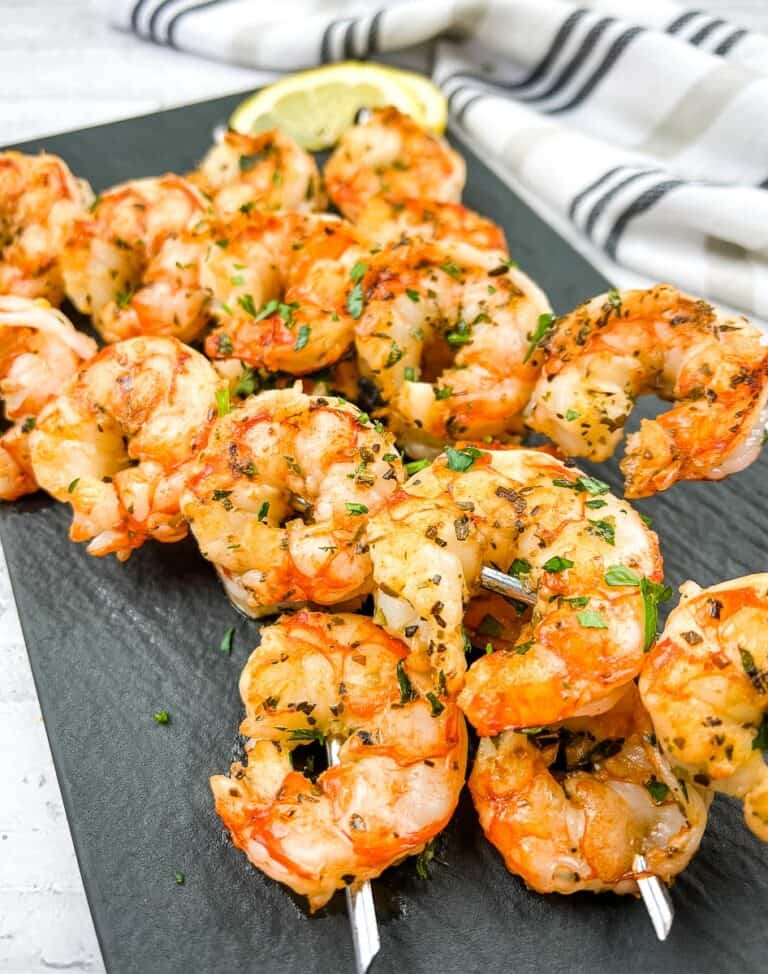 Mediterranean Grilled Shrimp on skewers on a black platter.