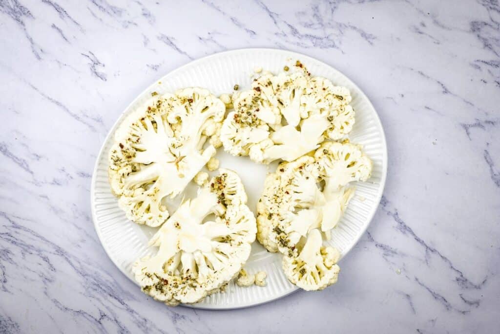 Cauliflower steaks with herb oil on a plate.