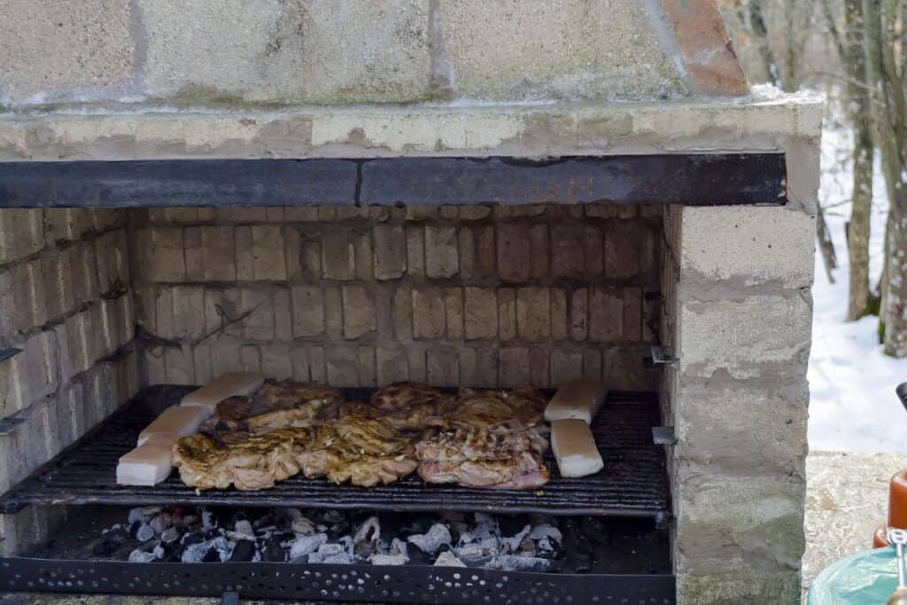 Part Of Stove Brick Masonry For Barbecue With Juicy Steaks Cooking On A Grill Over Embers.