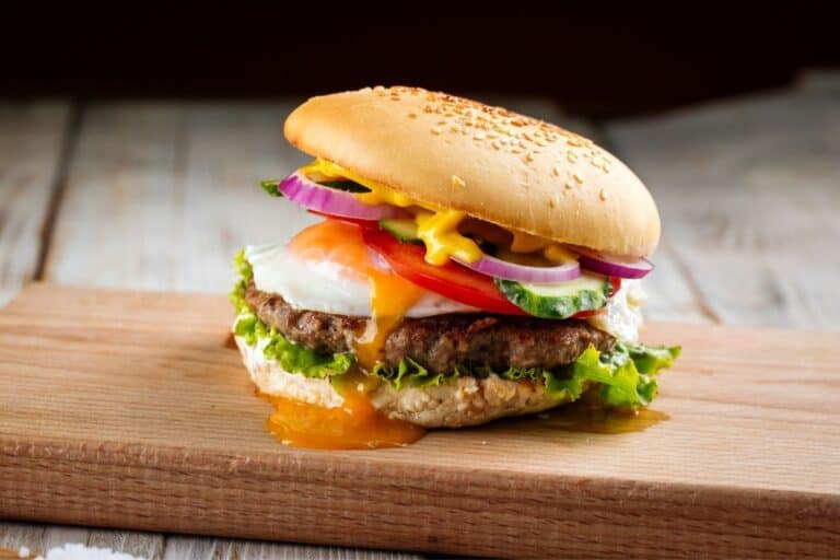 Classic burger with egg on the wooden board.