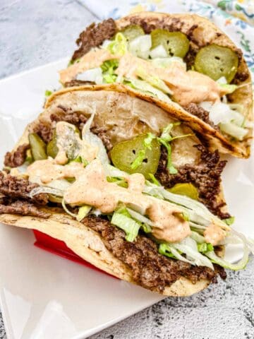 Two pieces of Blackstone Griddle Big Mac Tacos on a white plate.