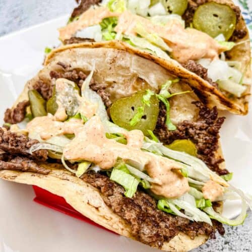 Two pieces of Blackstone Griddle Big Mac Tacos on a white plate.