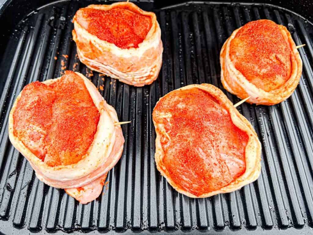 Place the bacon-wrapped chicken breasts on the grill.