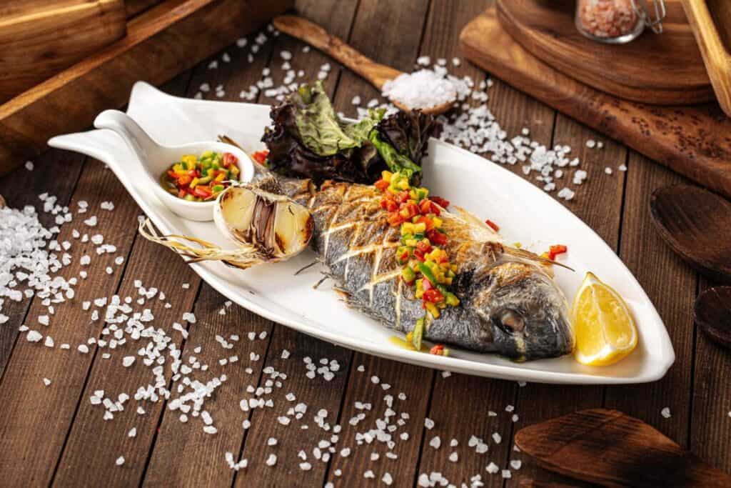 Appetizing grilled fish on the wooden background.