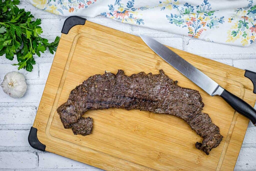 Top-down shot of Carne Asada on a board with a knife.
