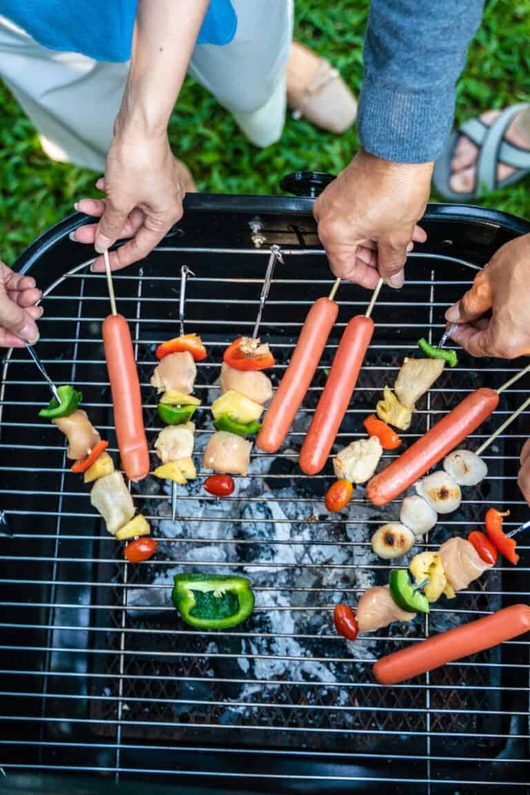 People's hand grilling BBQ in home garden.