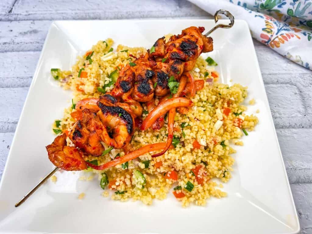 Grilled Harissa-Honey Chicken Skewers on a white plate.