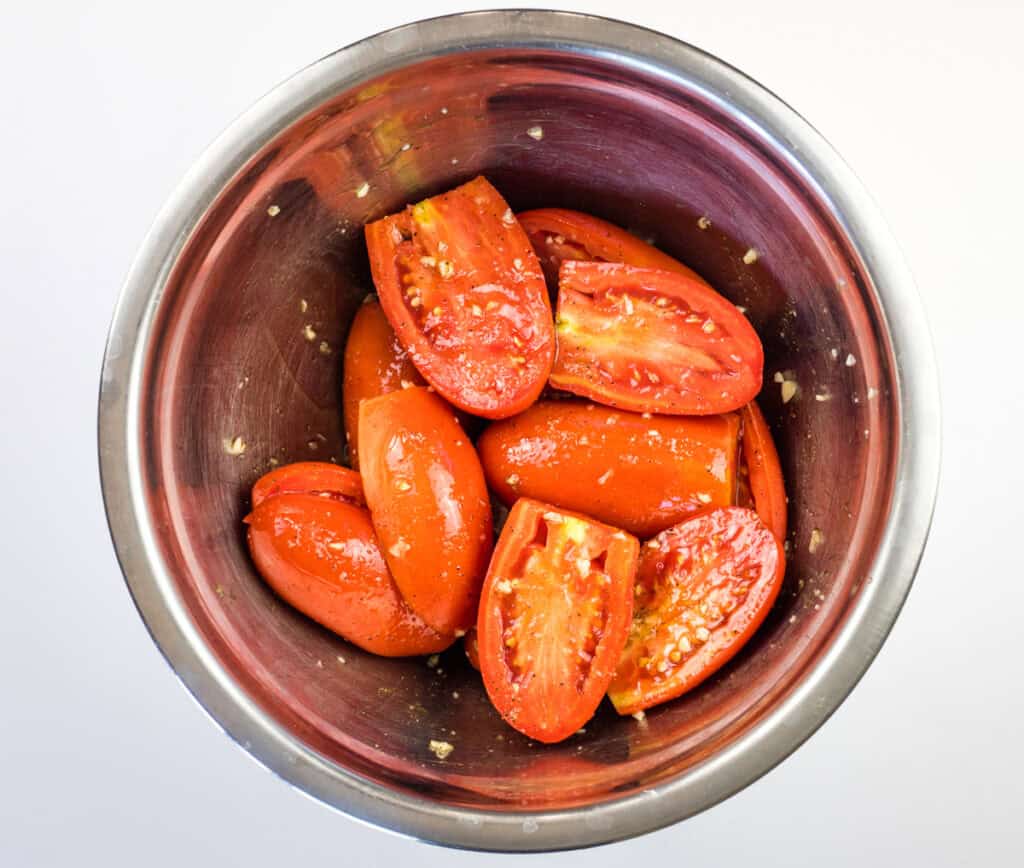 Wash tomatoes, remove stems, and halve them.