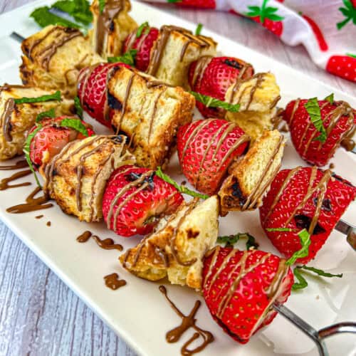 Three pieces of Grilled Strawberry Shortcake Skewers on a plate.