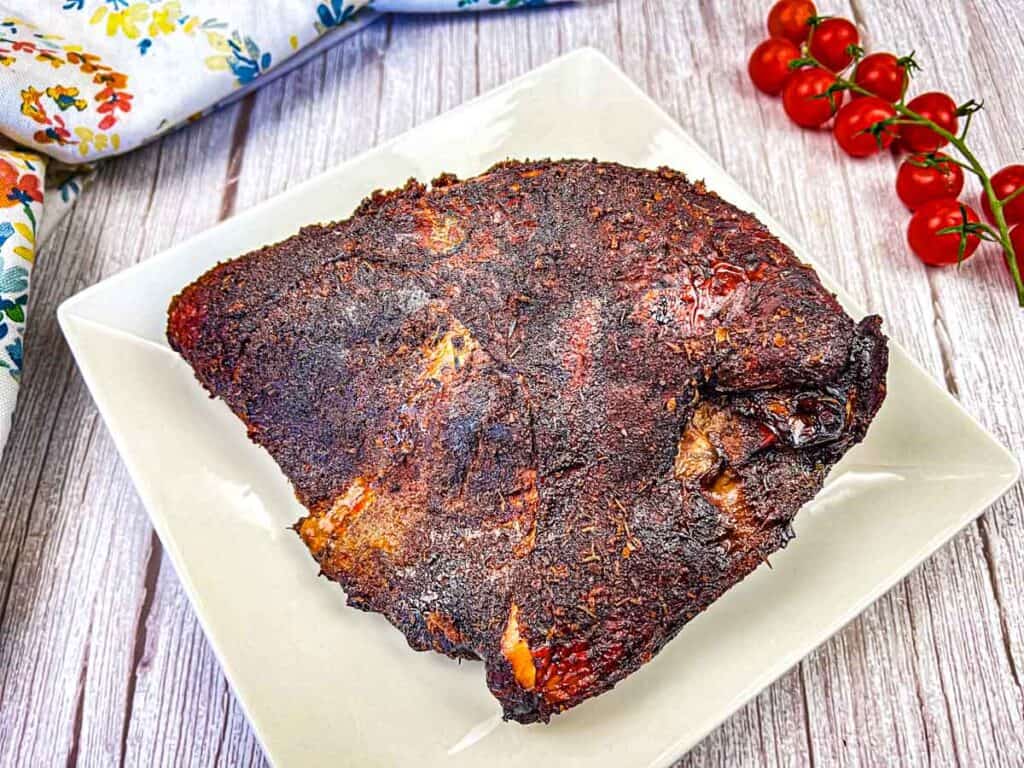 A smoked turkey breast on a white plate.