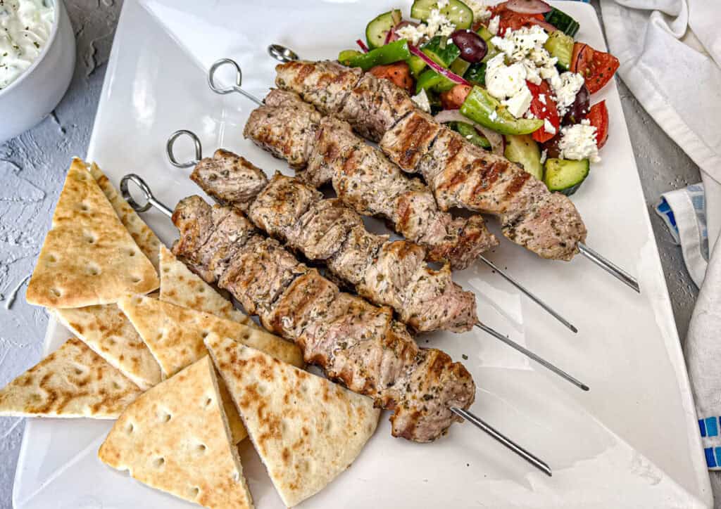 Top-down shot of Ninja Woodfire Pork Souvlaki with Horiatiki Salad on a white plate.