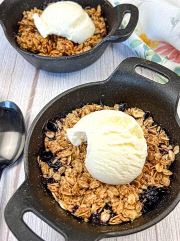 Two bowls of Smoked Berry Crisp with an ice cream on top.