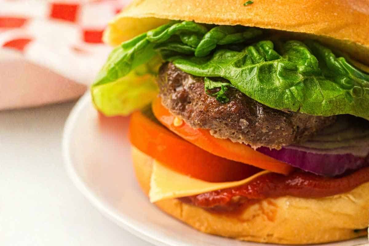 Close-up Grilled Beef Burgers on a white round plate.