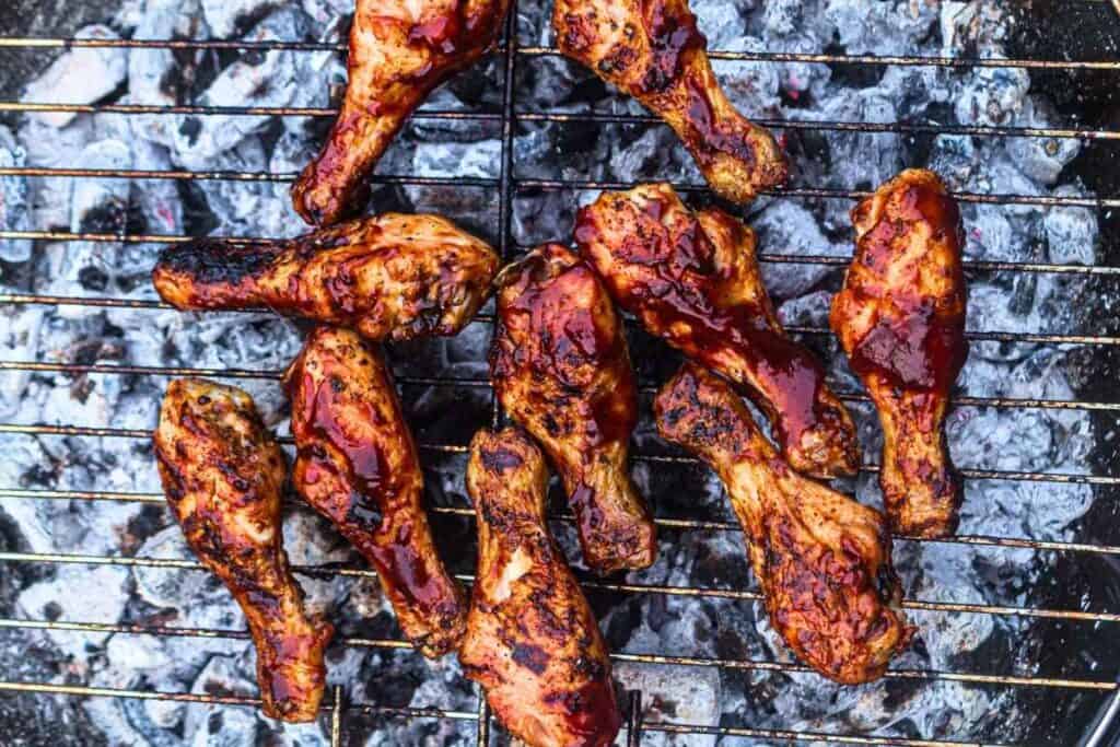 Ten pieces of grilled chicken drumsticks on the grill.