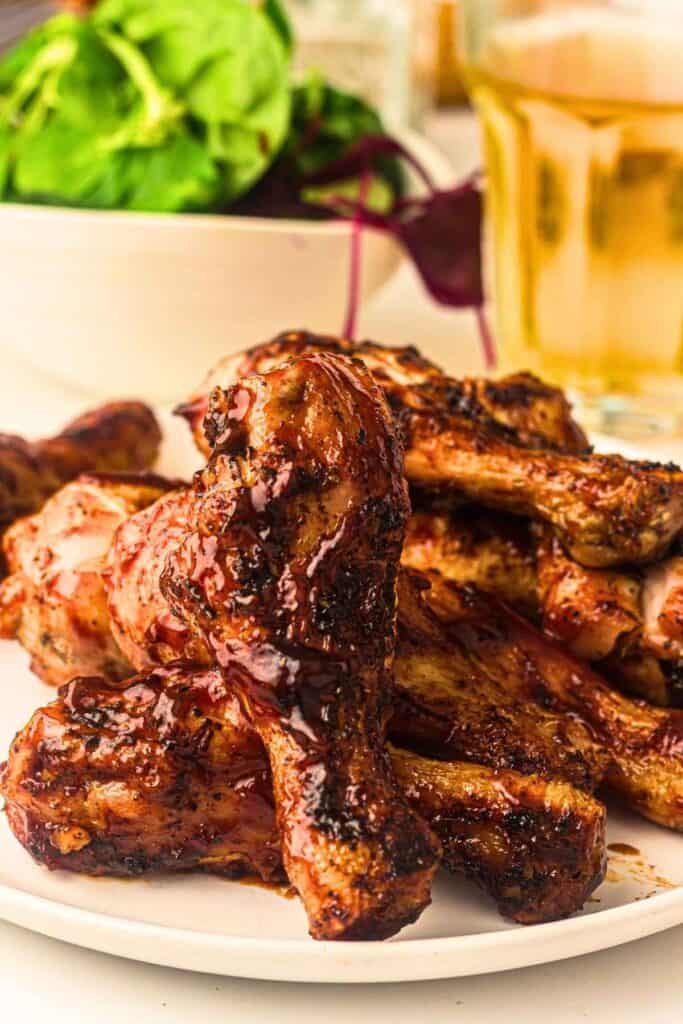 A white plate of grilled chicken drumsticks.