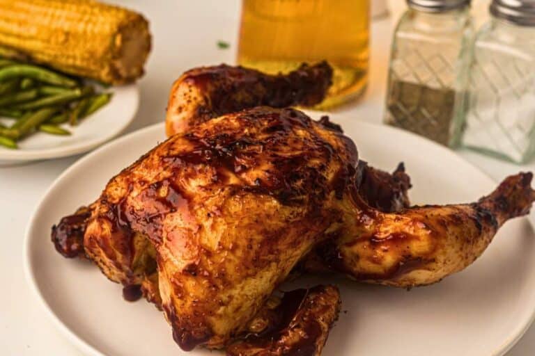 Grilled whole chicken glazed with BBQ sauce on a plate.