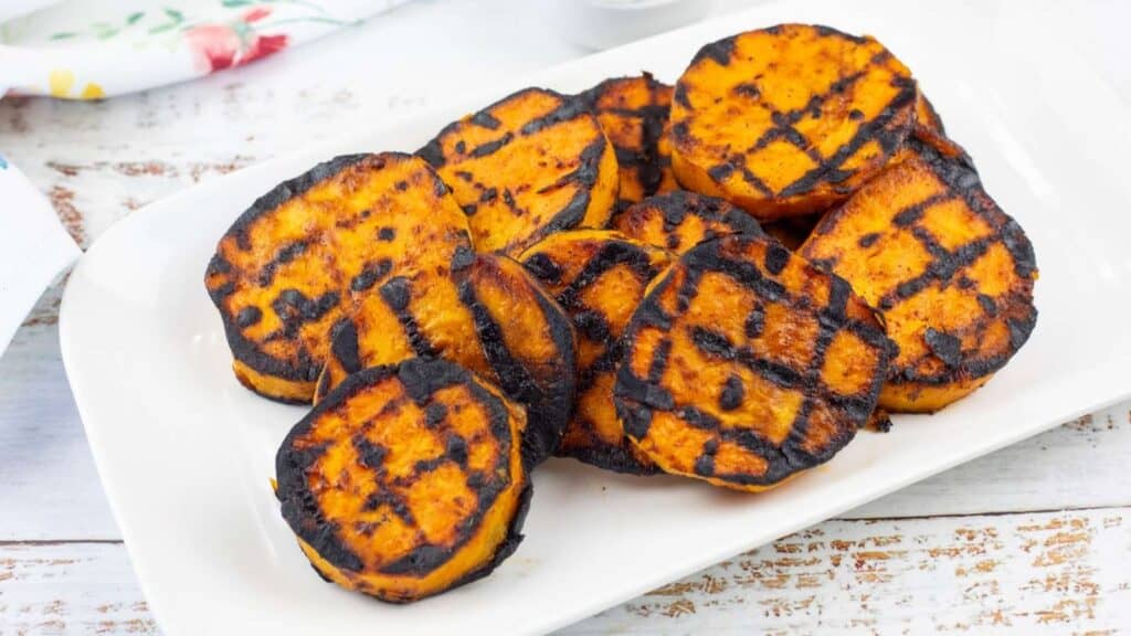 Grilled Sweet Potatoes with Cilantro-Lime Yogurt Sauce on a square white plate.