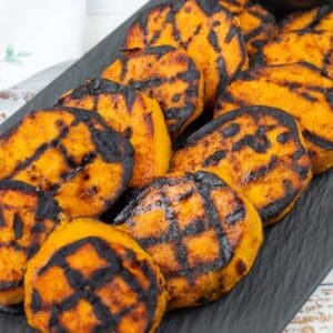 Grilled Sweet Potatoes with Cilantro-Lime Yogurt Sauce on a black slate plate.