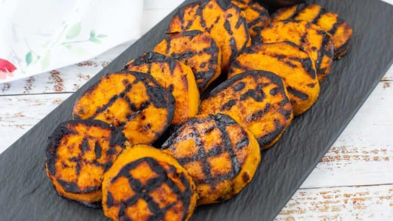 Grilled Sweet Potatoes with Cilantro-Lime Yogurt Sauce on a black slate plate.
