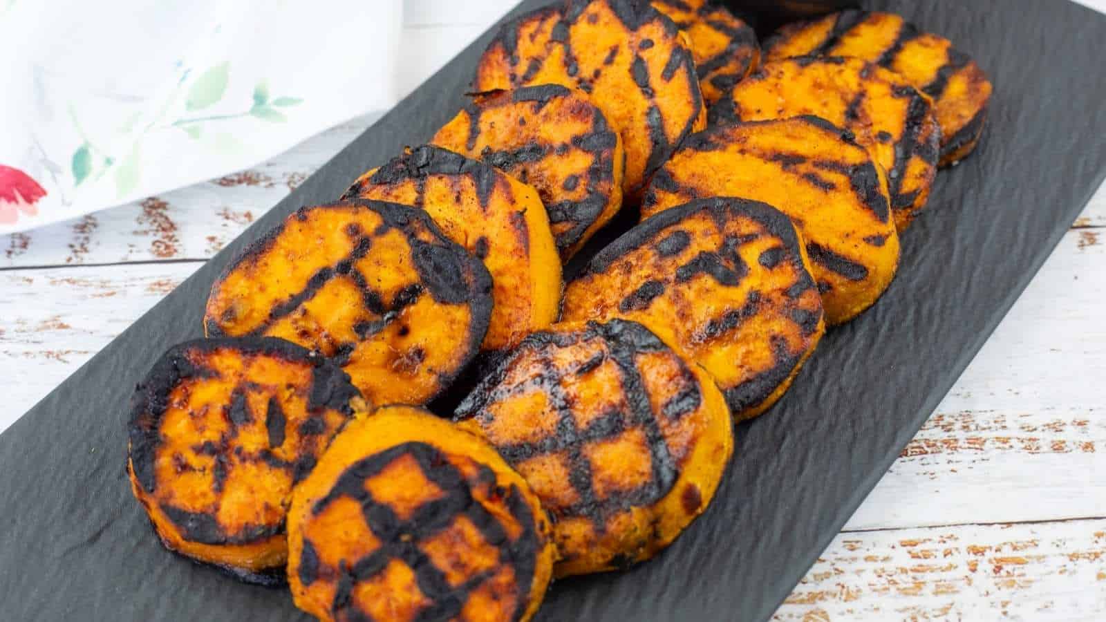 Grilled Sweet Potatoes with Cilantro-Lime Yogurt Sauce on a black slate plate.