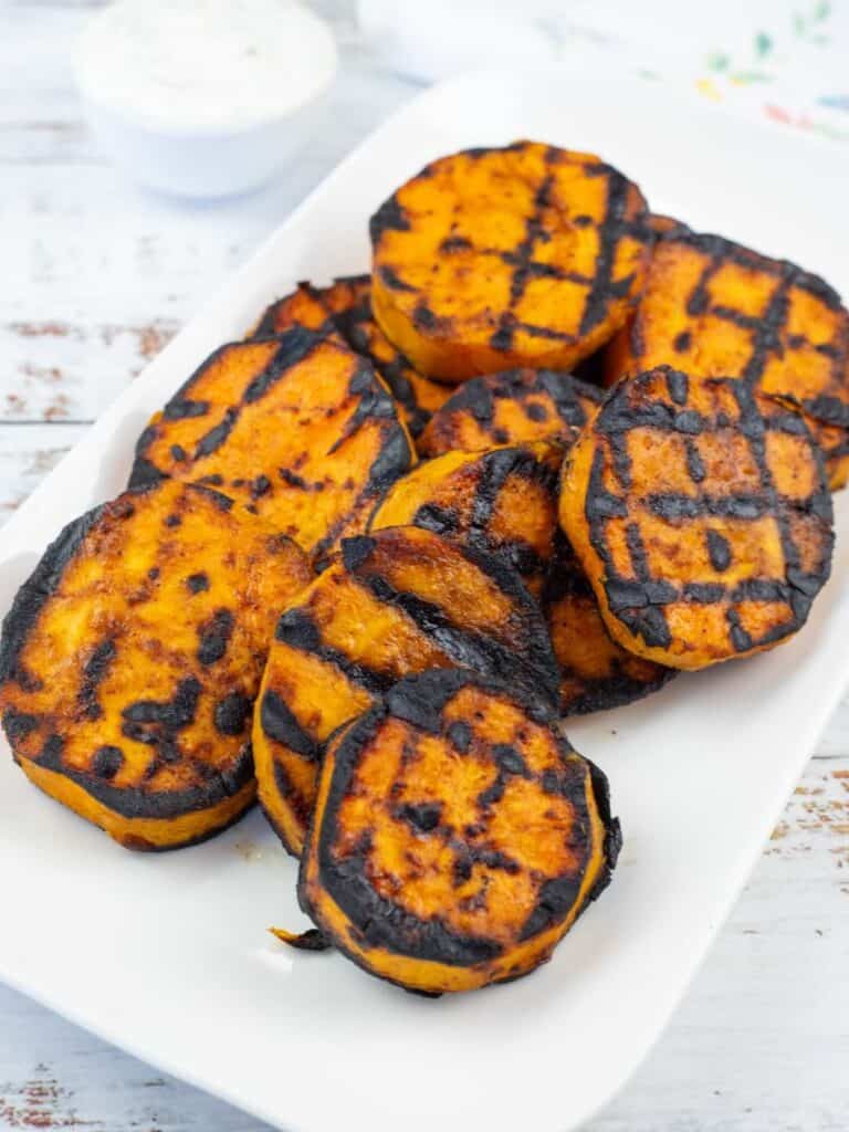 Grilled Sweet Potatoes with Cilantro-Lime Yogurt Sauce on a white rectangular plate.