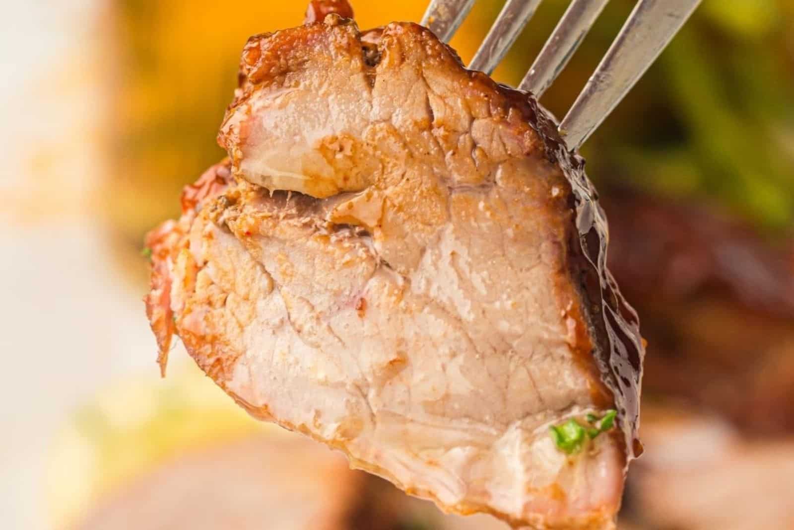 A fork holding a piece of Grilled Pork Tenderloin.