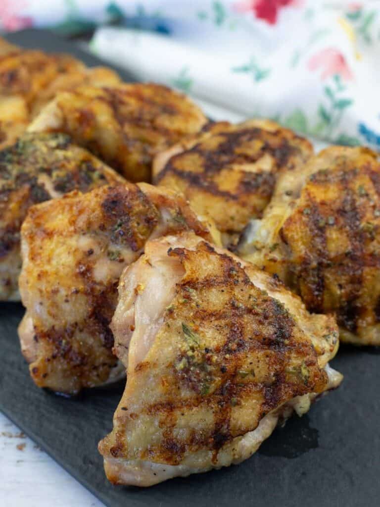 A slate plate with a pieces of Grilled Dijon Rosemary Chicken Thighs.