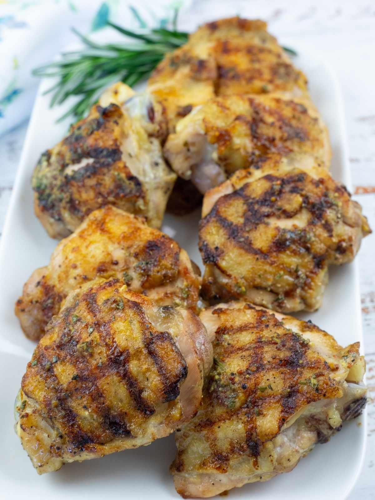 Grilled Dijon Rosemary Chicken Thighs on a white plate.